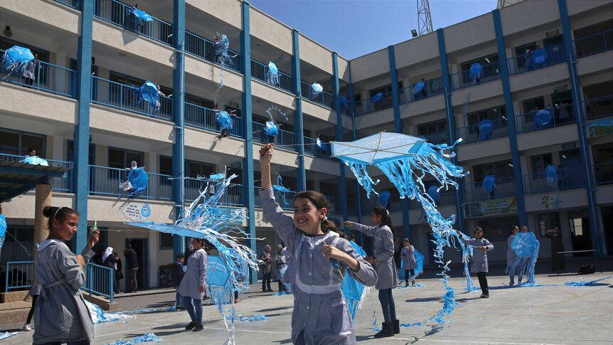 School girls are seen flying blue kites.