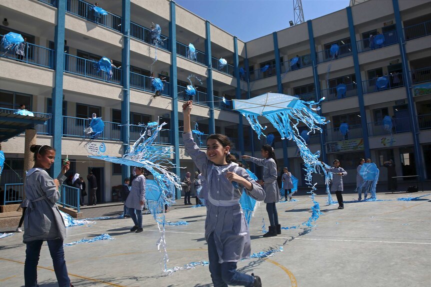 School girls are seen flying blue kites.