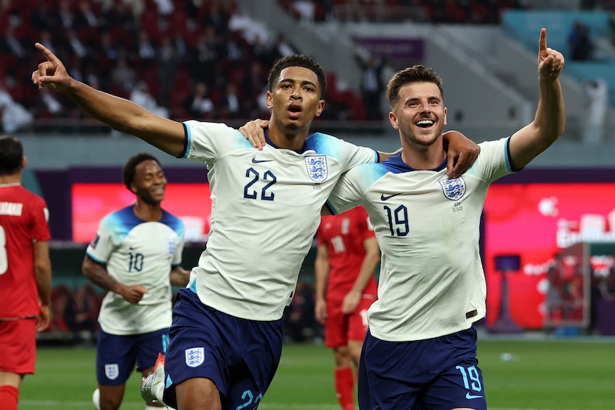 Two football players standing next to each other and signing in celebration after score. 