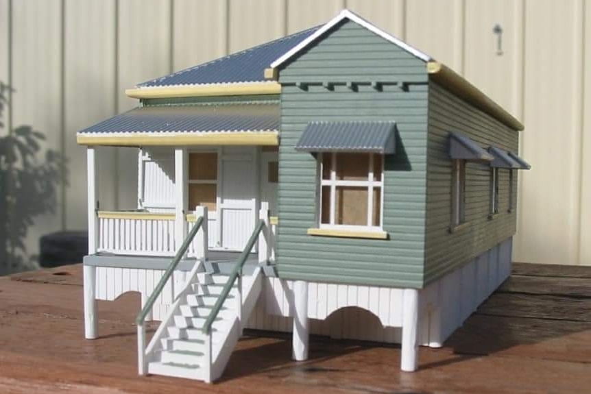 A small model of a green and white timber house.