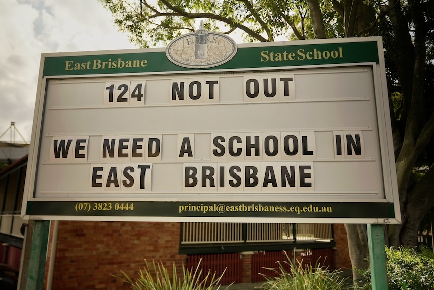 A sign outside East Brisbane State School reads '124 not out, we need a school in East Brisbane'