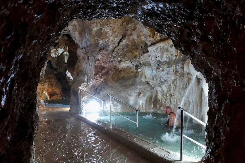 A man sitting inside a spa inside a cave