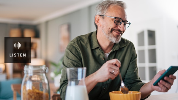 A man having breakfast and looking at a mobile phone. Has Audio.