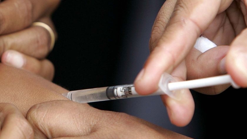 Close up of needle in arm as a child receives a measles vaccination.