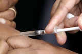Close up of needle in arm as a child receives a measles vaccination.