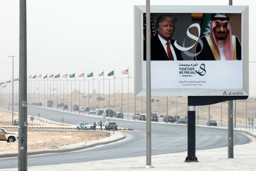 A billboard shows Donald Trump and Saudi Arabia's King Salman. Trump's motorcade can be seen in the distance