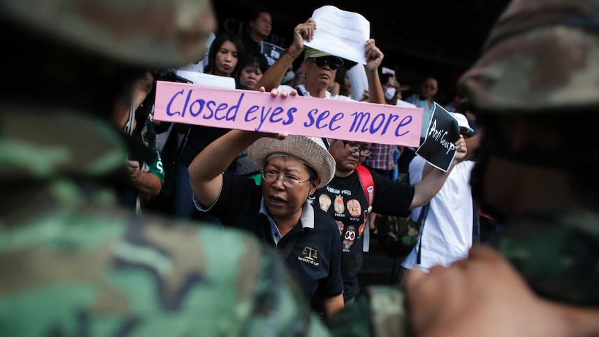 Anti-military protesters hold signs in Bangkok