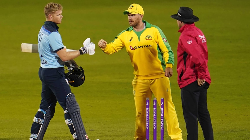 A batsman and a fielder bump fists at the end of a one-day international cricket match.