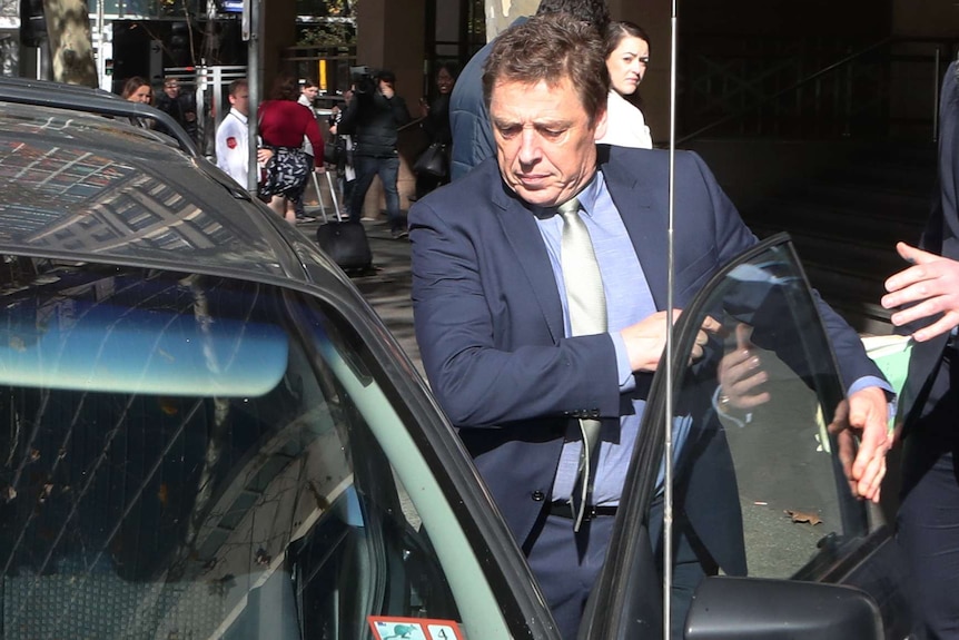 Mark 'Bomber' Thompson, dressed in a suit, gets into a car.