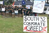 Crowd of people and sign saying "South 32 Corporate Greed"