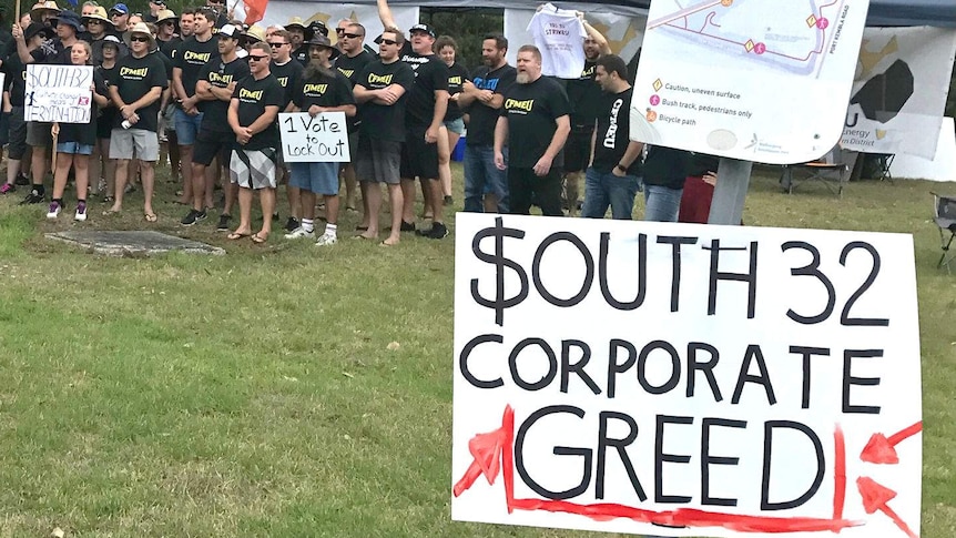 Crowd of people and sign saying "South 32 Corporate Greed"