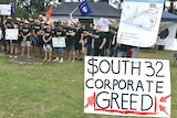 Crowd of people and sign saying "South 32 Corporate Greed"