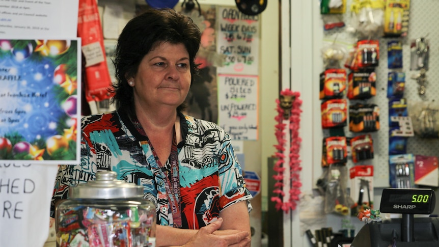 A woman stands behind a counter in a general store.