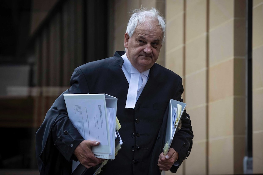 Daryl Coates carries books outside a courthouse.