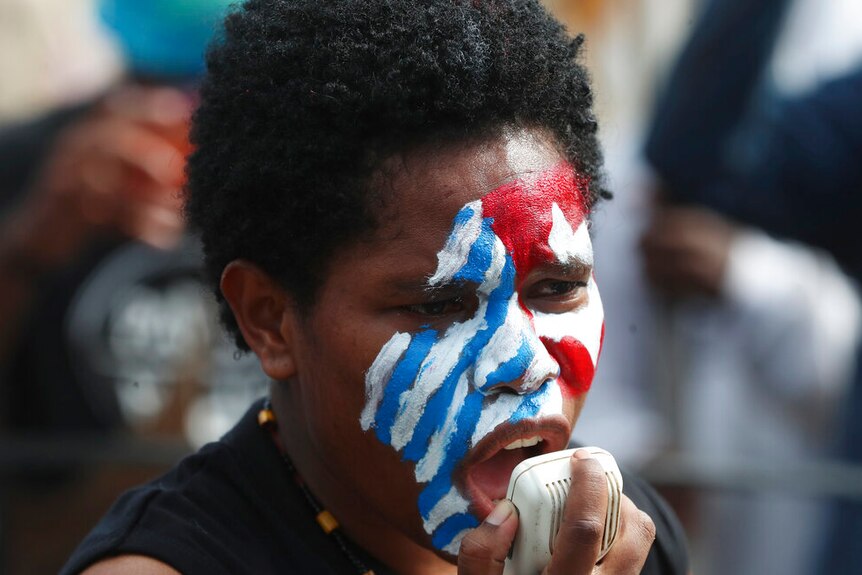 A supporter of the independence of the West Papua with face painted with the colors, white, red and blue.
