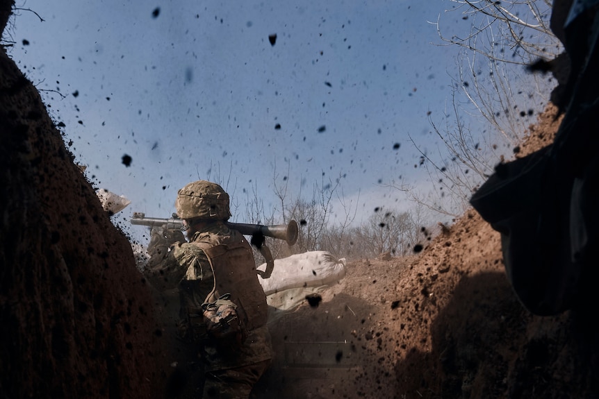 A Ukrainian soldier of the 28th brigade fires a grenade launcher from inside a bunker.