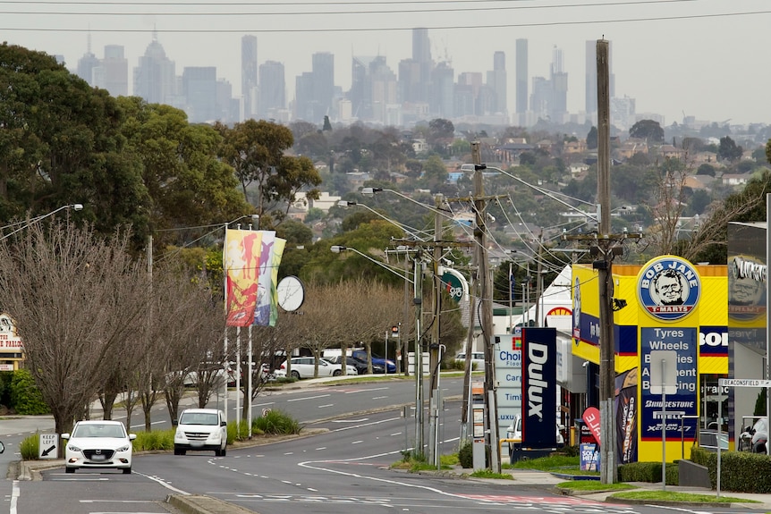 The CBD skyline of towers is visible from an elevated suburban road, on an overcast wintry day.