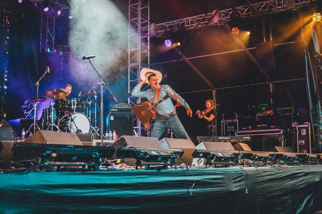 Um músico tocando com uma banda através de um chapéu no meio da multidão.