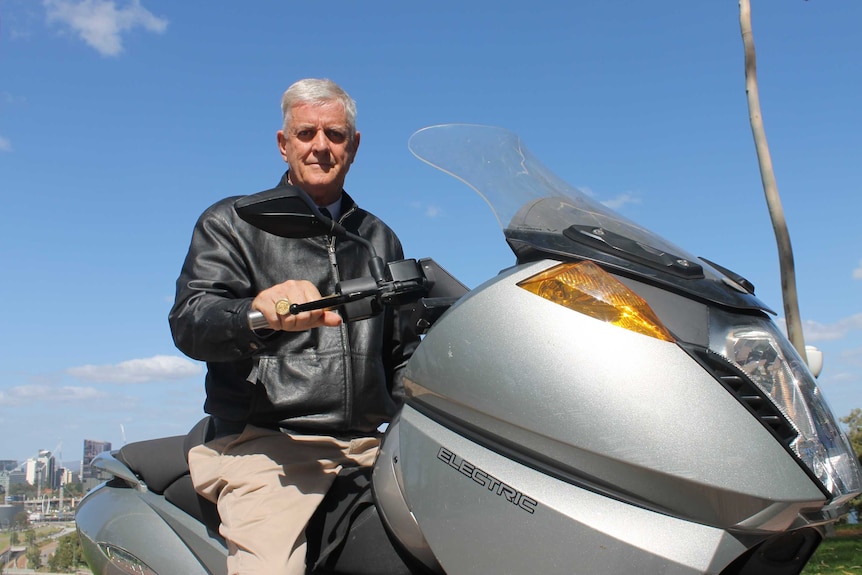 Ian porter sitting on his electric scooter with a blue sky in the background