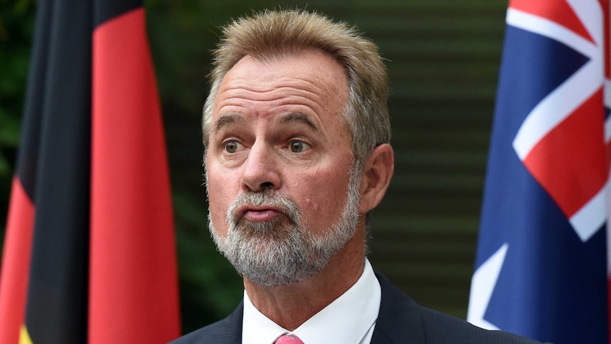 Nigel Scullion with the Aboriginal and Australian flags