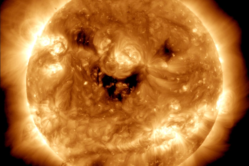 Close-up of the sun with dark spots resembling a smile. 