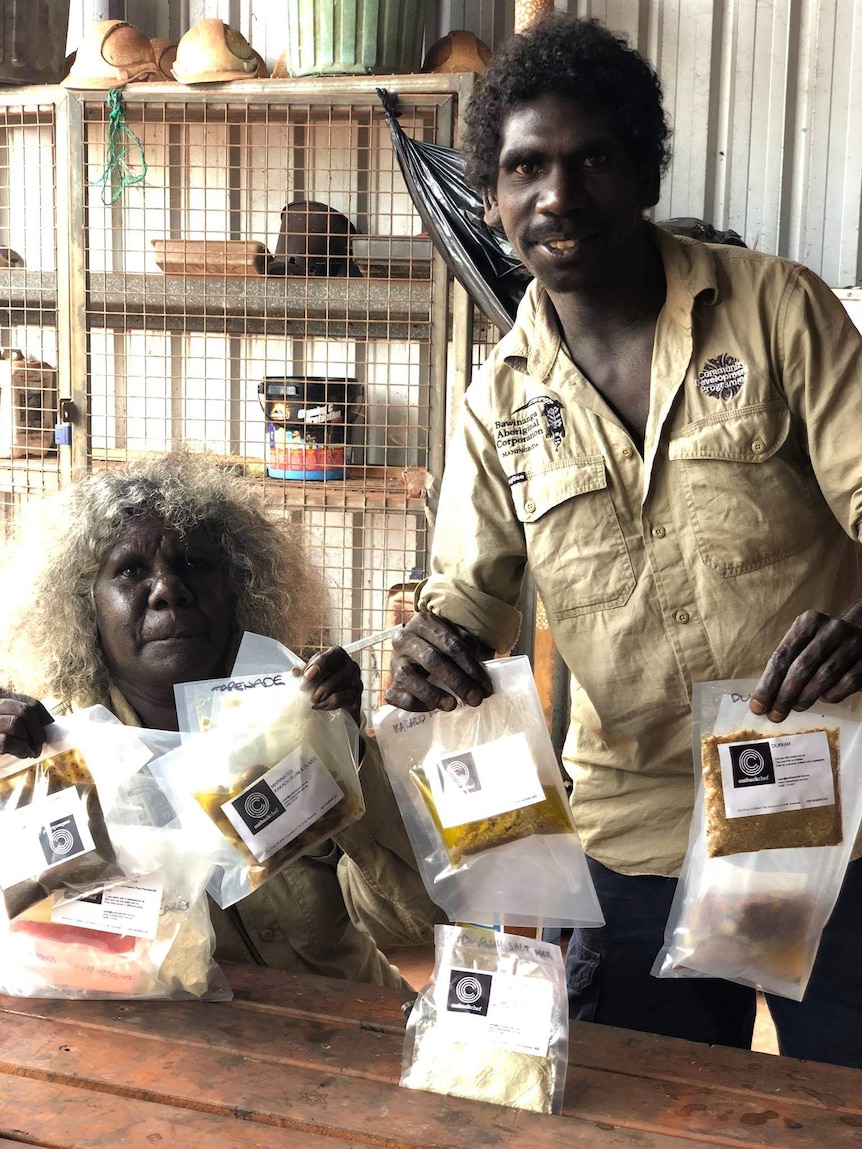An Aboriginal man and woman hold up bags of sample bush tucker products.
