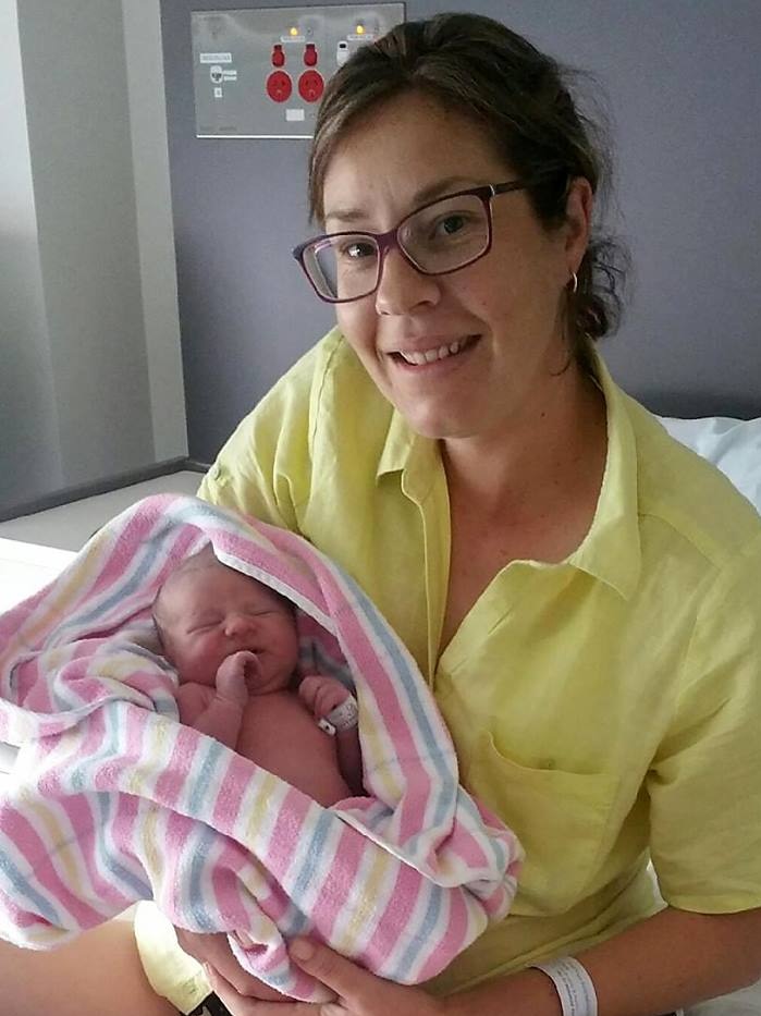 Mum Lisa Sommerell in a hospital room holding newborn baby Annika in a striped blanket