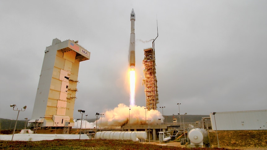 a rocket launches in front of a gloomy grey sky at night