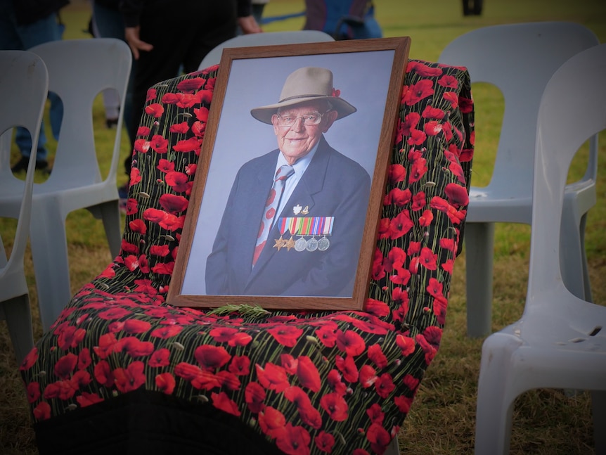 A chair with poppy fabric draped over it, and a framed photo of Sydney on it.