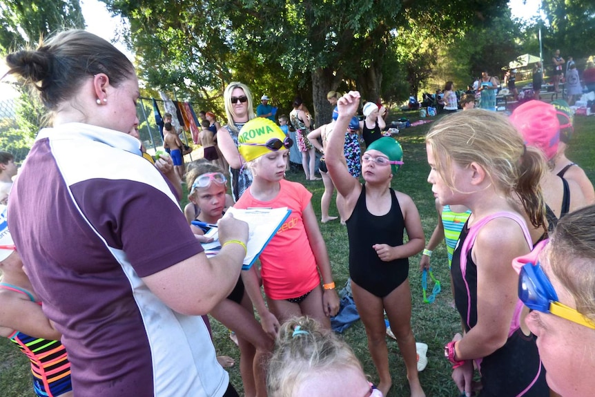 A swimming coach confers with local kids competing in the Shine Shield in Jugiong, NSW.