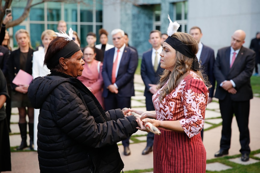 Price stands wearing ceremonial clothing in a Parliament House courtyard.