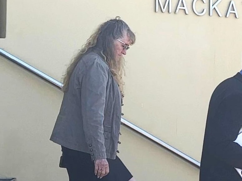 A woman in her 60s with long hair walks down courthouse steps with a lawyer in front of her