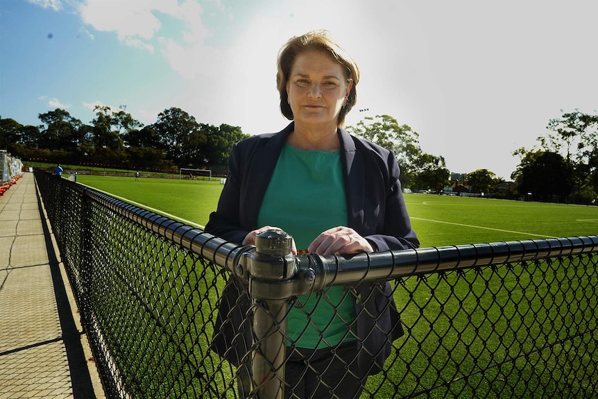 A woman stands at the corner of a soccer field.