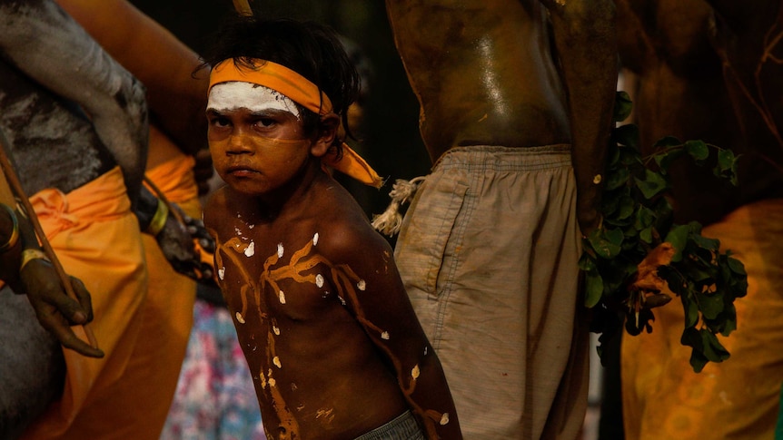 A young boy near the age of six dances in traditional dress.