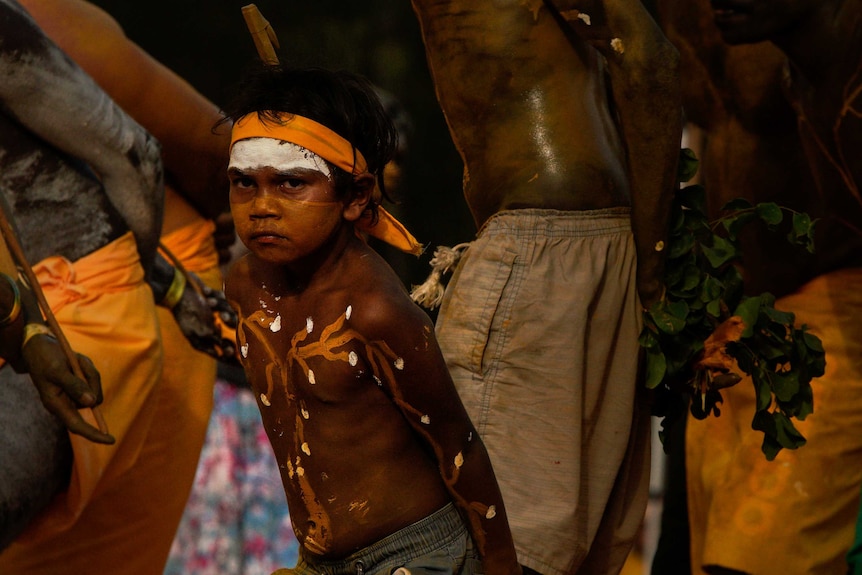 A young boy near the age of six dances in traditional dress.