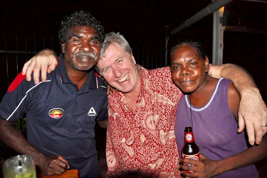 Three people pose with their arms around each other's shoulders