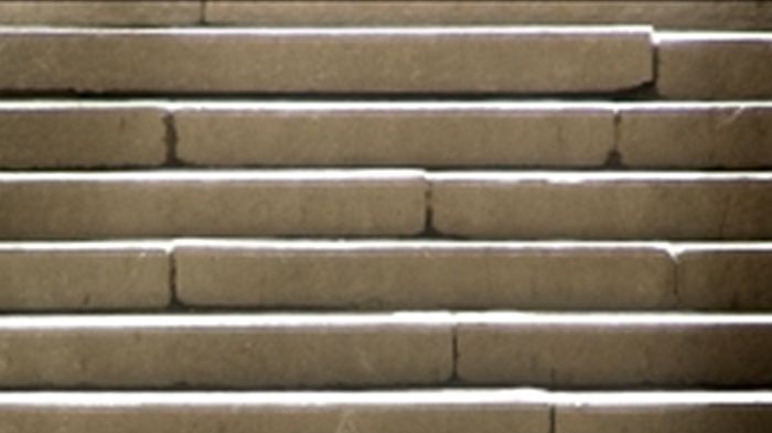 A beggar sitting at the bottom of a flight of stairs