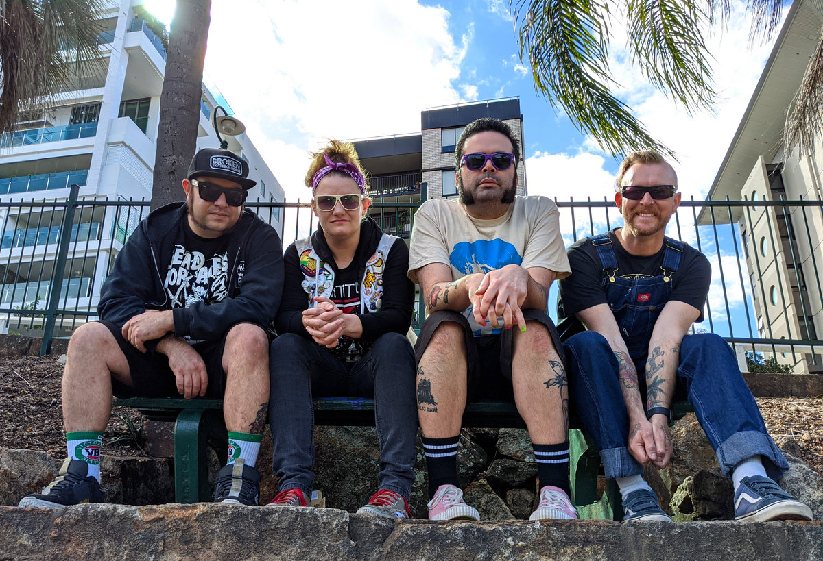 Four members of Brisbane DIY punk band Flangipanis posing in casual clothes on concrete step