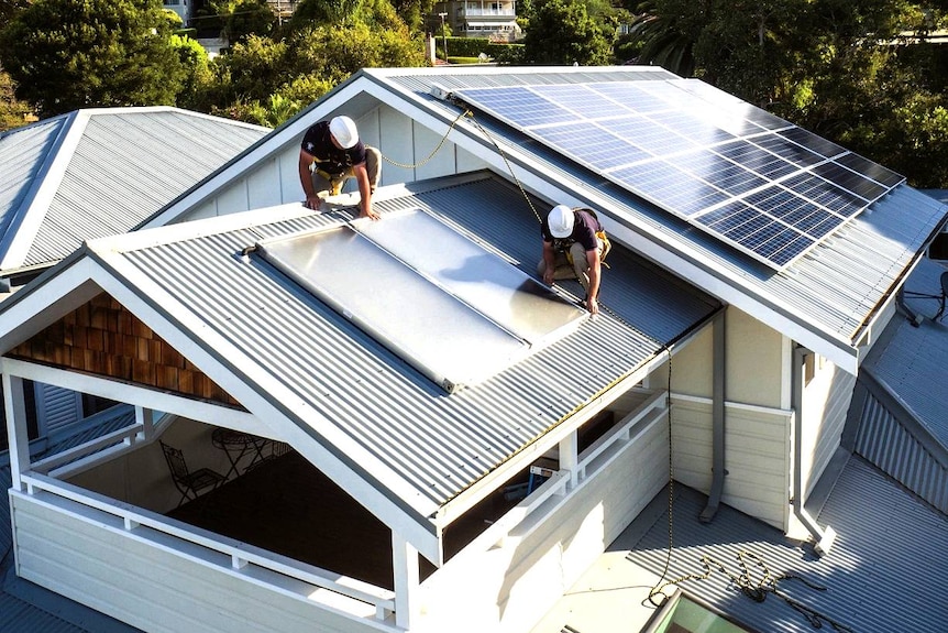 Workers carry out solar installation on a household rooftop.