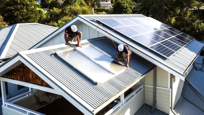 Workers carry out solar installation on a household rooftop.