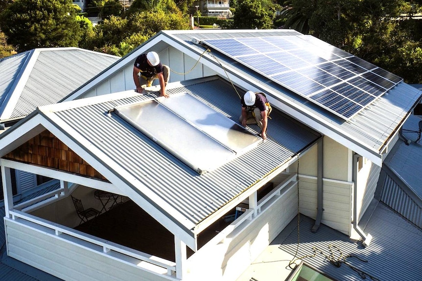 Les travailleurs effectuent une installation solaire sur un toit de maison.