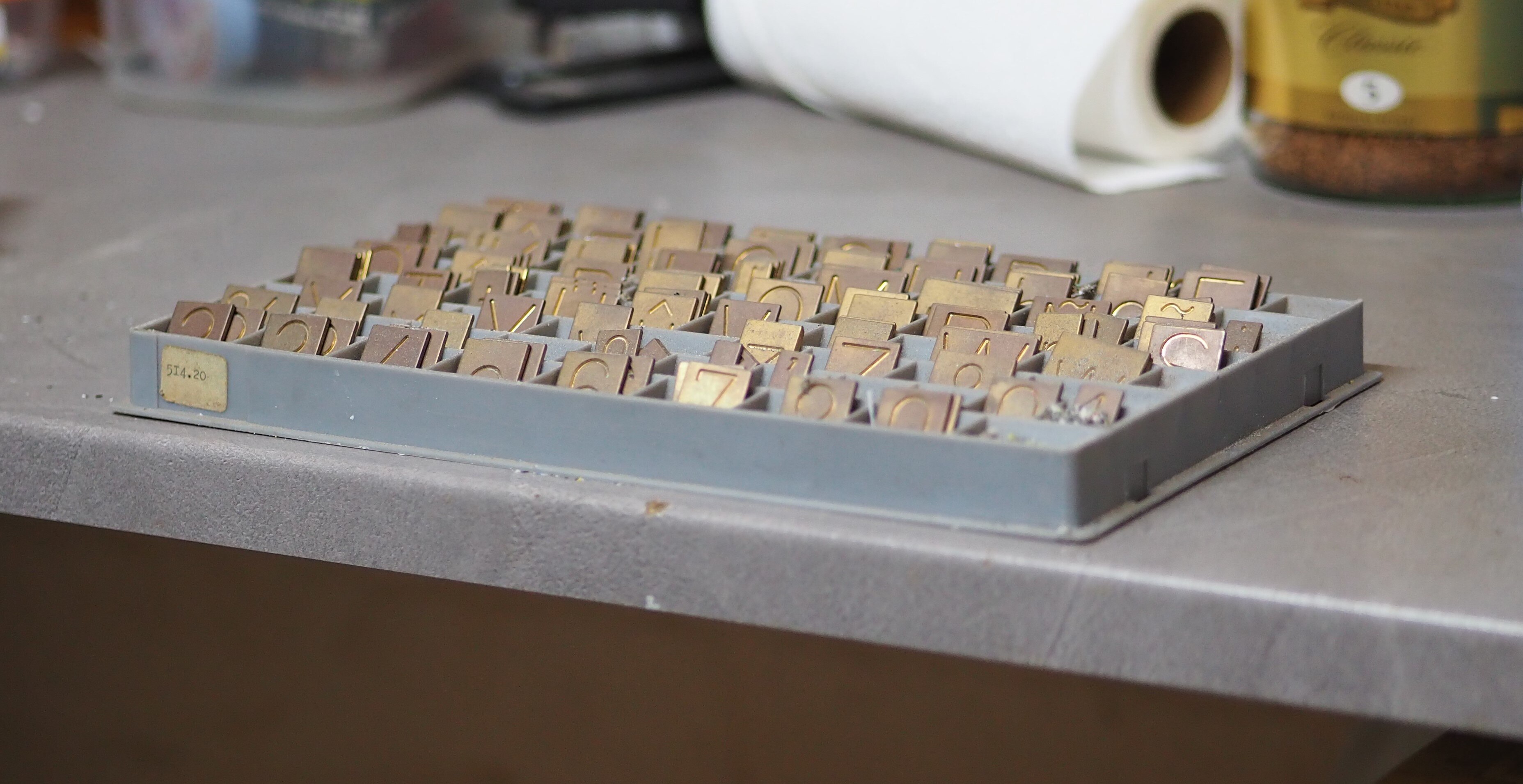 Las baratijas de grabado de letra dorada en un conjunto, cada una con números o letras. Sentado en un banco gris.