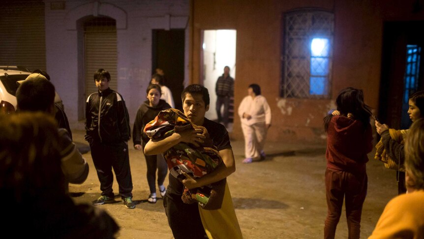 Chileans wait on a street outside their houses after powerful earthquake hits central coast