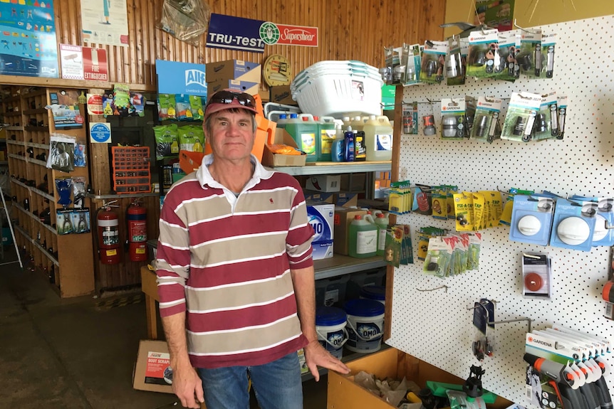 A man in a striped jersey standing in front of a hardware store.