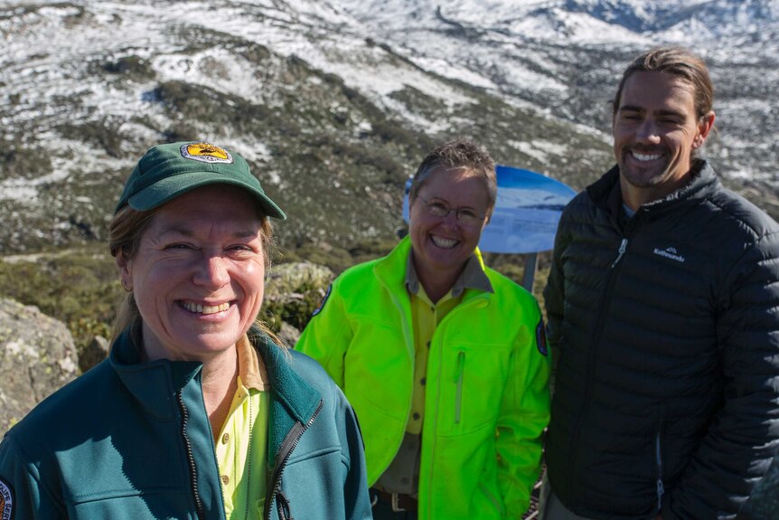 Hillary Cherry, Jo Caldwell and Ryan Tait stand on the mountainside, smiling.