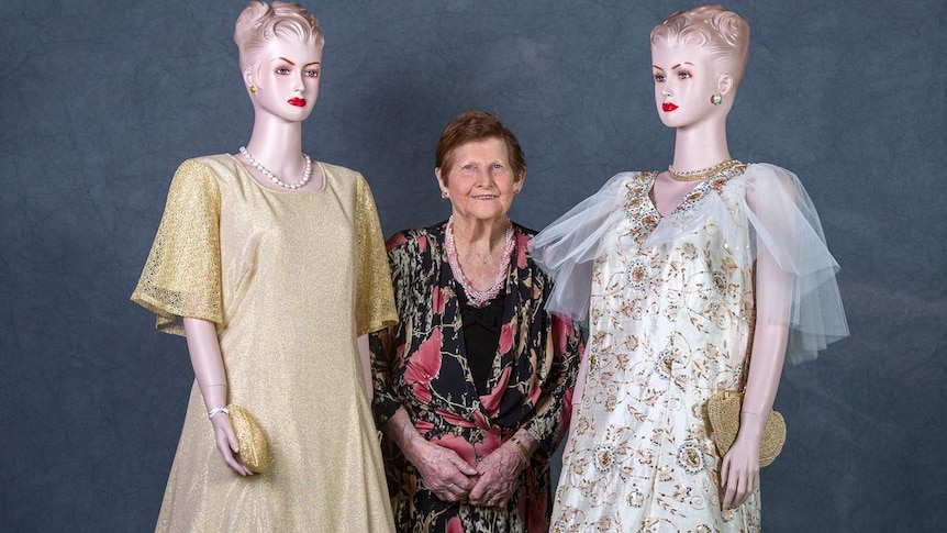 A woman stands between two mannequins