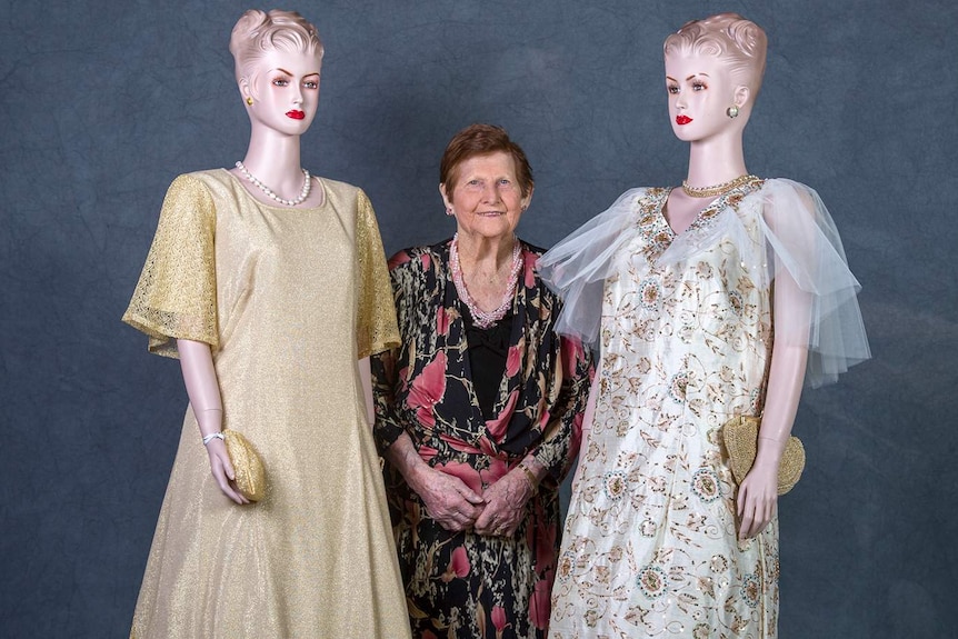 A woman stands between two mannequins