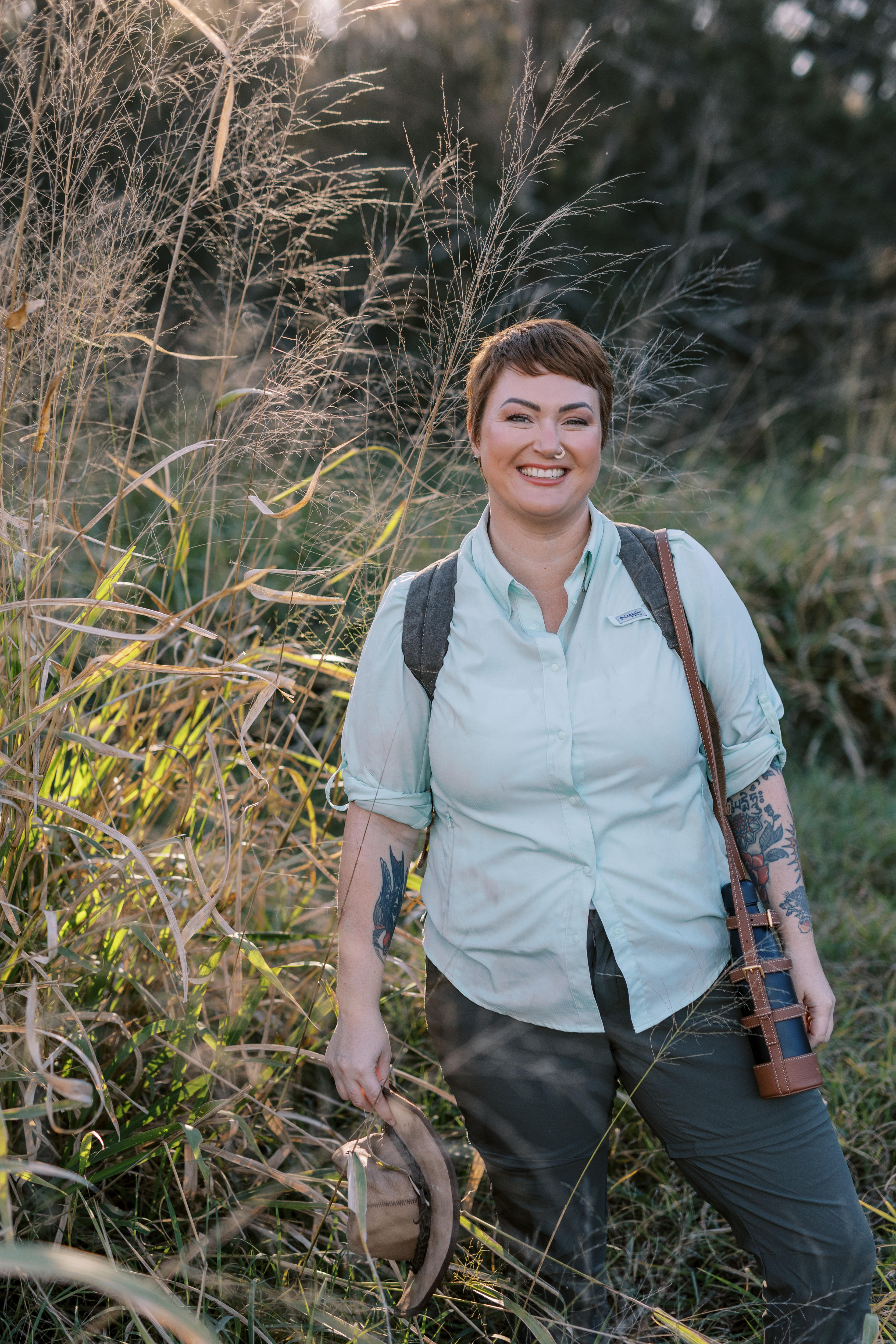 Monique Ross wears a backpack and holds her hat while in nature.