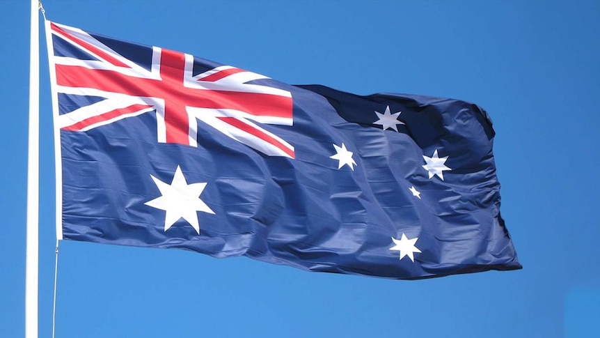 Australian flag on top of a flag pole flowing in the wind