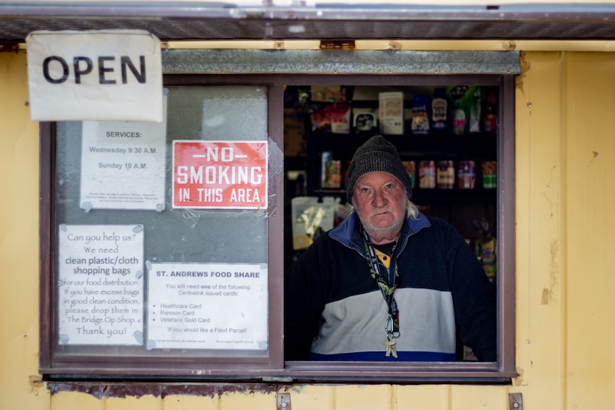 A man stands behind a sliding window looking out.